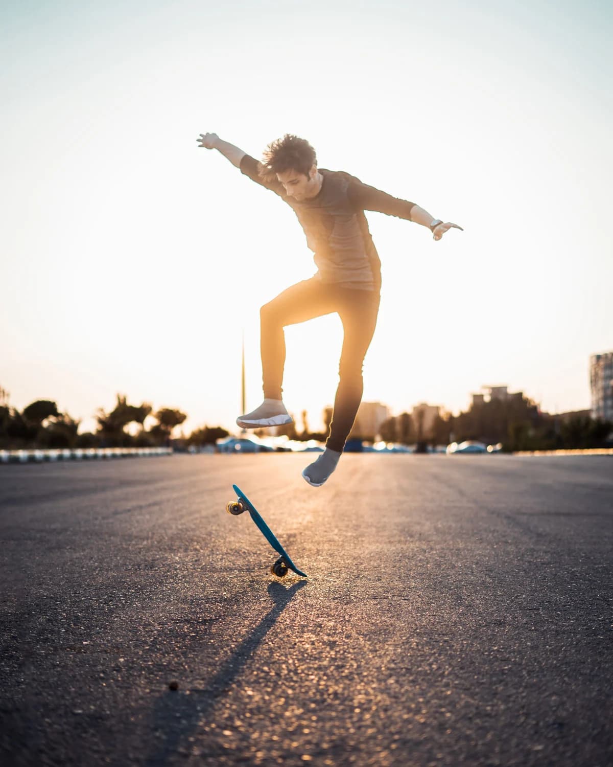 Foto original de un skater saltando en el aire sobre una tabla inclinada en una plaza al atardecer